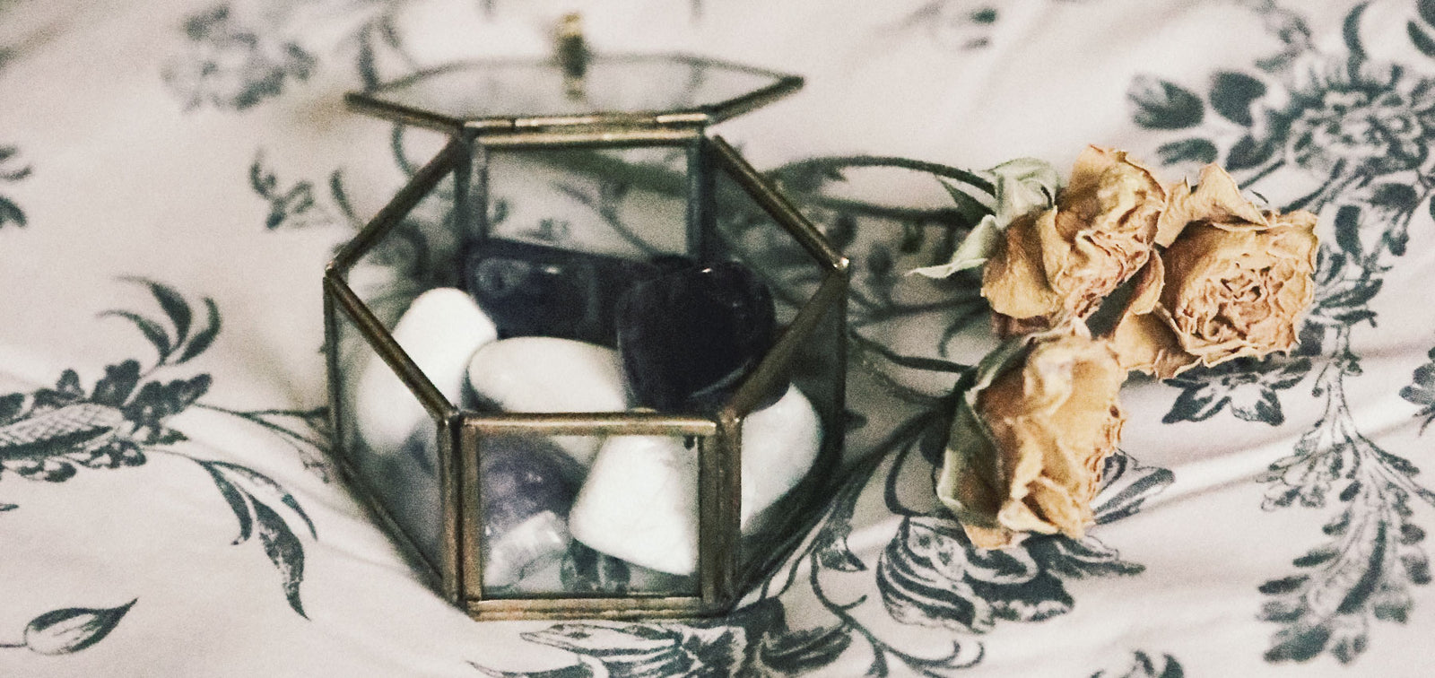 Tumbled crystals in class box with yellow flowers on a bed