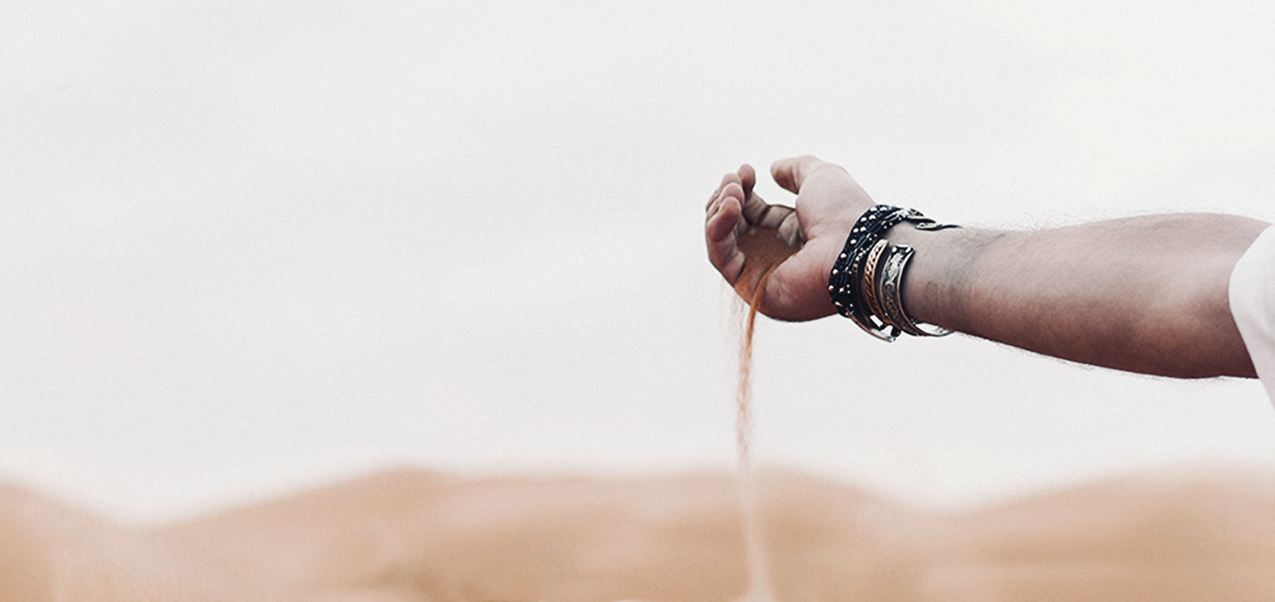 Hand with sand falling out of it with desert in the background